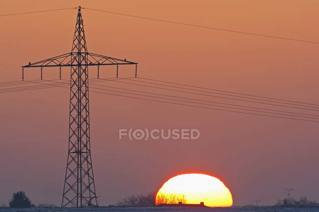 Germania, tramonto oltre al traliccio elettrico — Foto stock