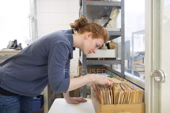 Женщина в мастерской глядя на карты индекс — стоковое фото