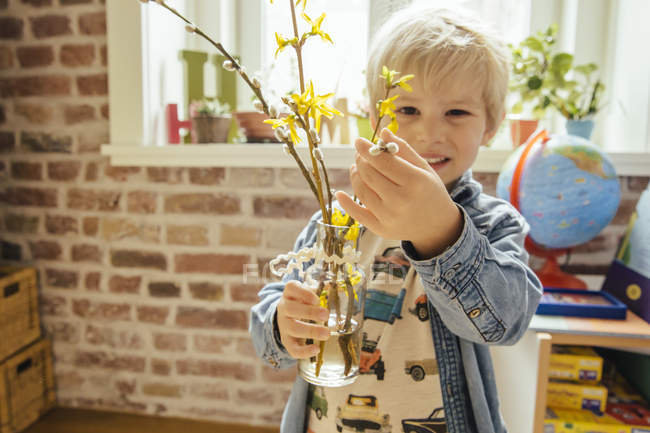 Menino segurando vaso com salgueiro e forsythia — Fotografia de Stock