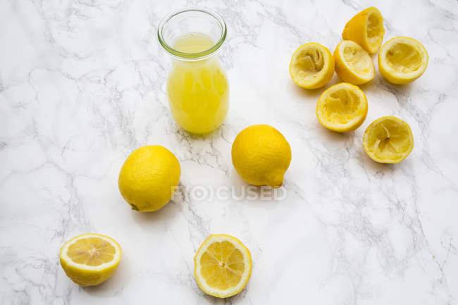 Zumo de limón recién exprimido y limones orgánicos - foto de stock