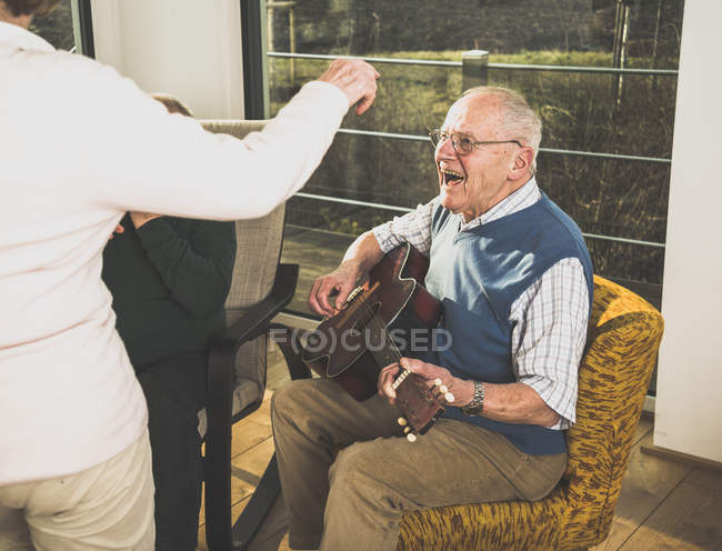 Hombre mayor tocando la guitarra para personas mayores bailando - foto de stock