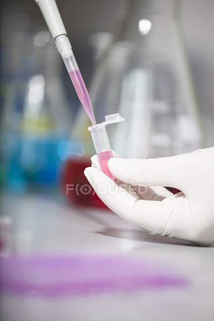 Close-up of scientist pouring liquid in test tube — Stock Photo