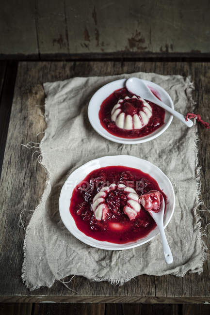 Close-up of Panna Cotta dessert with raspberry sauce on wooden table — Stock Photo