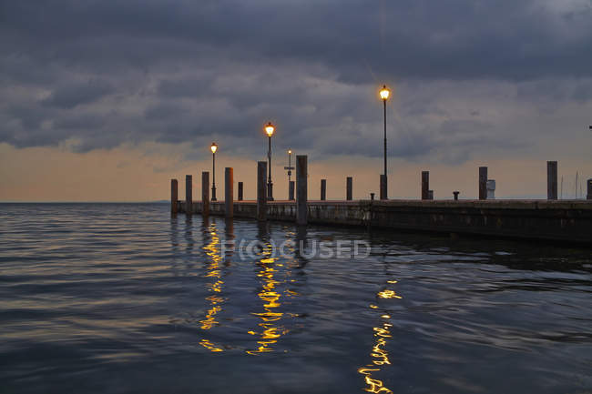 Italy, Garda, Lake Garda, pier with lanterns in the evening — Stock Photo