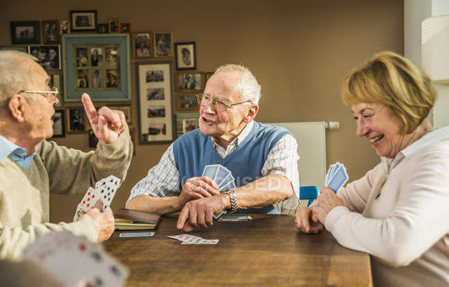 Senioren spielen Karten am Holztisch — Stockfoto
