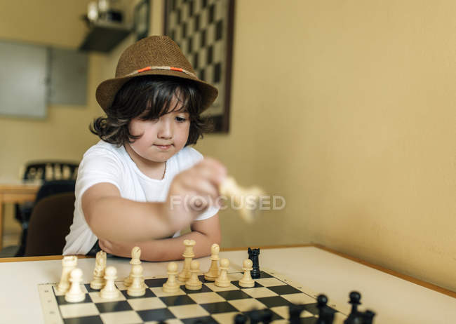 Елементарна вік хлопчика в капелюх гри в шахи в приміщенні — стокове фото