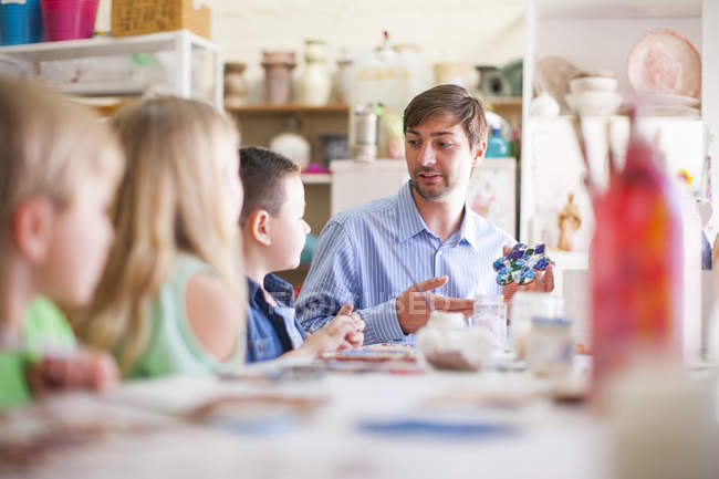 Male teacher in arts class talking to pupils — Stock Photo