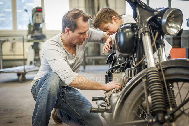 Padre e hijo manteniendo ciclomotor vintage en taller — hombre, Dos  personas - Stock Photo | #180249310