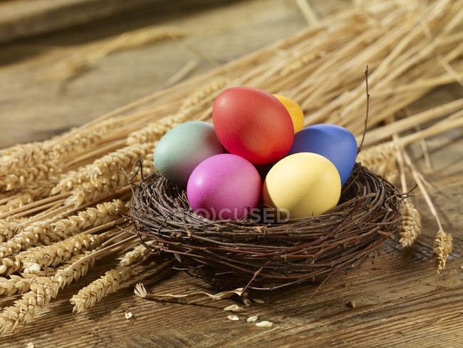 Primer plano de cuenco de huevos de Pascua multicolores en paja - foto de stock