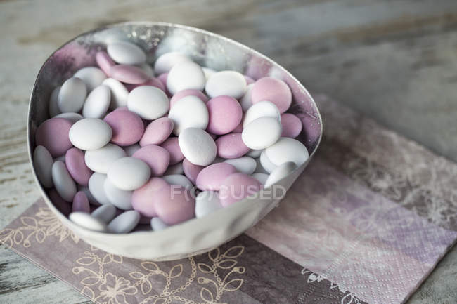 Bowl of white and pink chocolate beans on paper napkin — Stock Photo