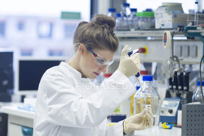 Биолог работает в лаборатории с пипеткой — стоковое фото