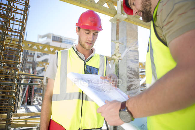 Lavoratori edili che discutono del piano edilizio in cantiere — Foto stock