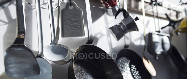 Pans and other utensils hanging at kitchen wall — Stock Photo