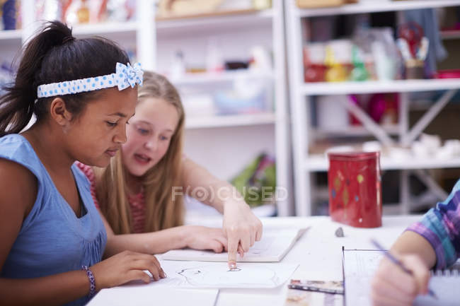 Two schoolgirls discussing paintings in art class — Stock Photo