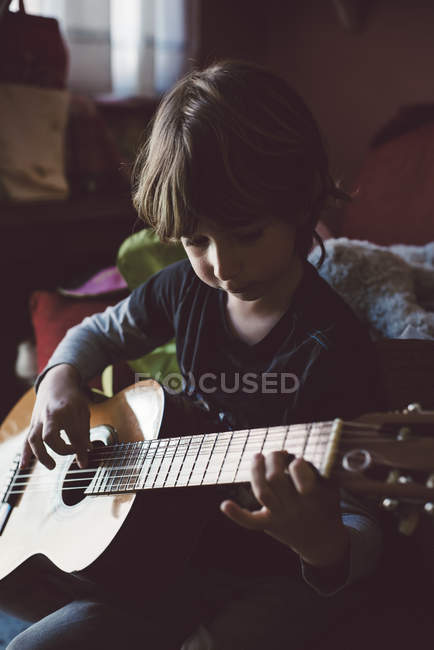 Petit garçon jouant de la guitare acoustique à la maison — Photo de stock