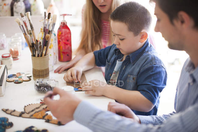 Boy tinkering in art class with classmate and teacher nearby — Stock Photo
