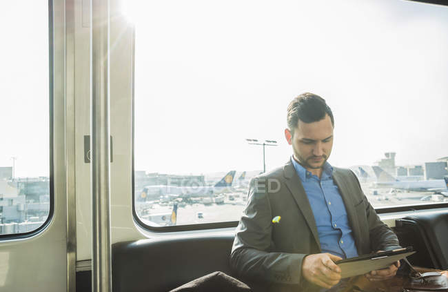 Giovane uomo d'affari che utilizza tablet digitale in autobus in aeroporto — Foto stock
