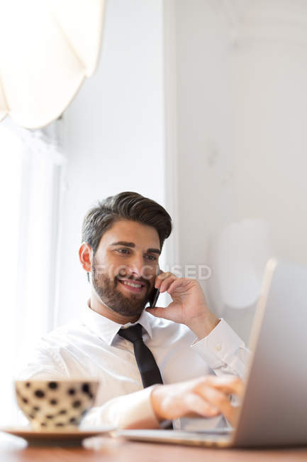 Бізнесмен з ноутбуком і чашкою кави на мобільний телефон — стокове фото