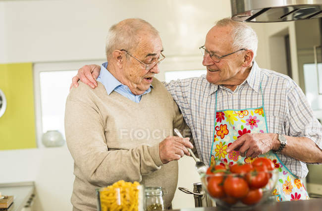 Two senior friends cooking in kitchen together — Stock Photo