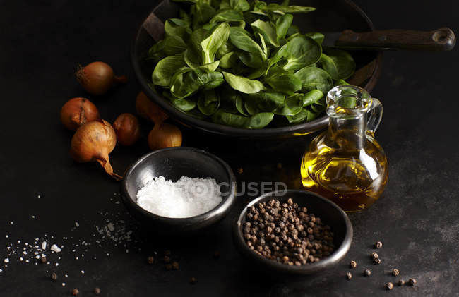 Lambs lettuce in bowl with pepper, salt and onions — Stock Photo