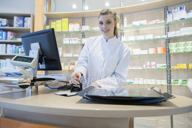Jeune pharmacien en pharmacie estampillage prescription — Photo de stock
