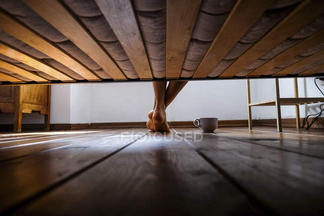 Abgeschnittenes Bild weiblicher Beine, die vom Bett aus auf dem Boden stehen — Stockfoto