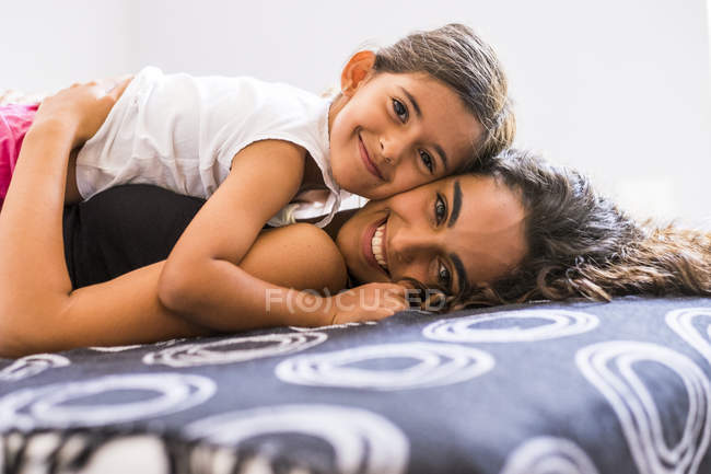 Porträt eines lächelnden Teenagermädchens und ihrer kleinen Schwester im Bett — Stockfoto