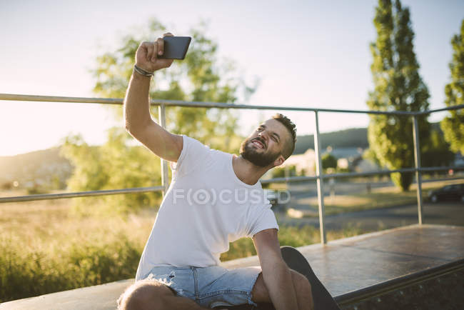 Skateboarder prendre selfie avec smartphone dans skatepark — Photo de stock