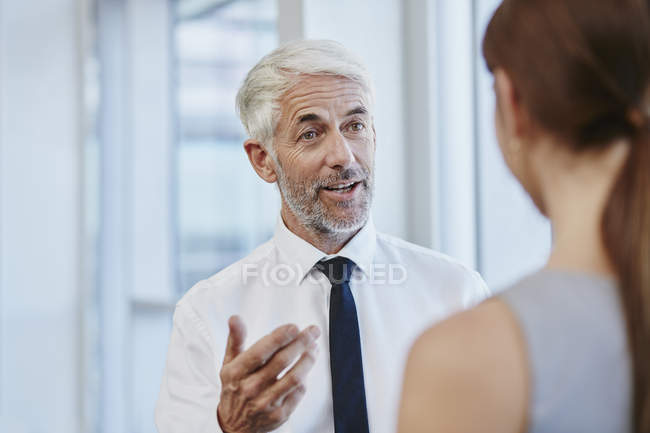Empresario hablando con empresaria en la oficina - foto de stock