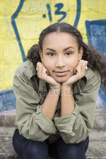Ritratto di adolescente con la testa tra le mani seduta davanti ai graffiti — Foto stock