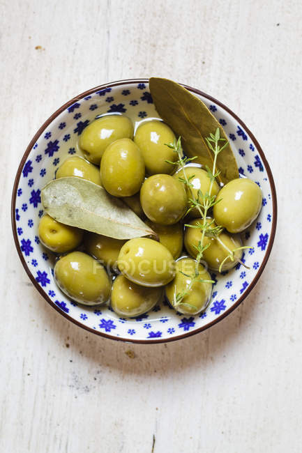 Azeitonas verdes em tigela com tomilho e folha de louro — Fotografia de Stock