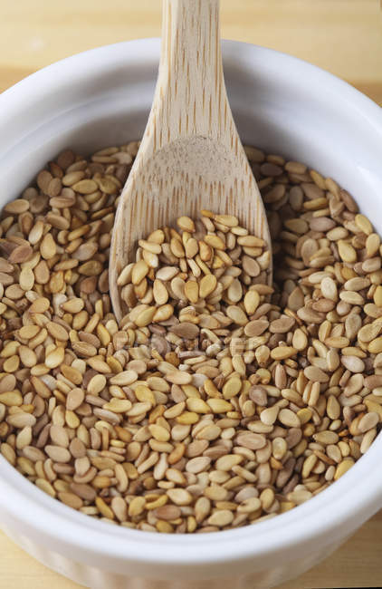 Sesame seeds in a bowl with wooden spoon, close-up — Stock Photo
