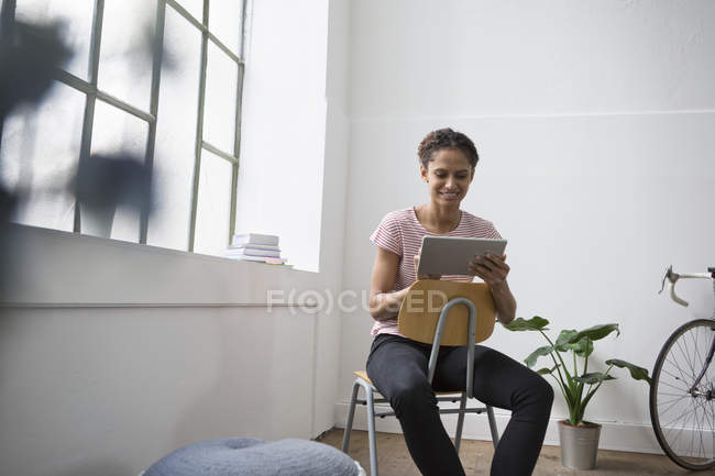 Mujer sentada en silla usando tableta digital - foto de stock