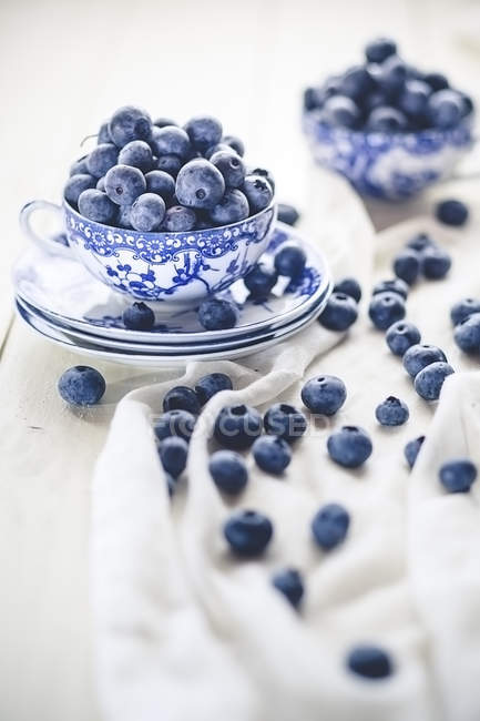 Blueberries in and around tea cup — Stock Photo