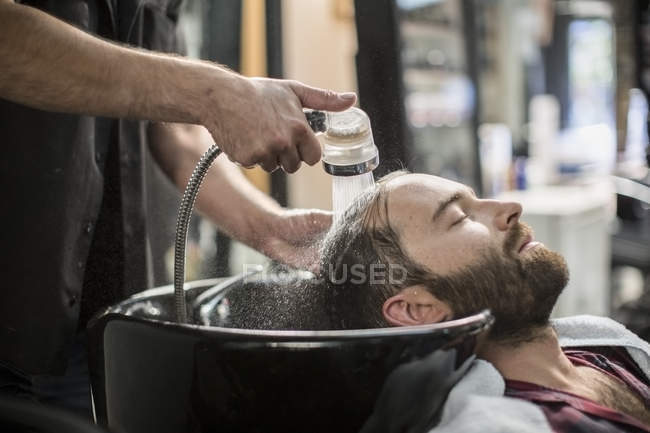 Cliente rilassato mentre si lava i capelli in barbiere — Foto stock