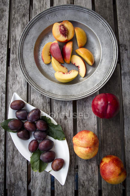 Plums and sliced nectarines on tray and table — Stock Photo