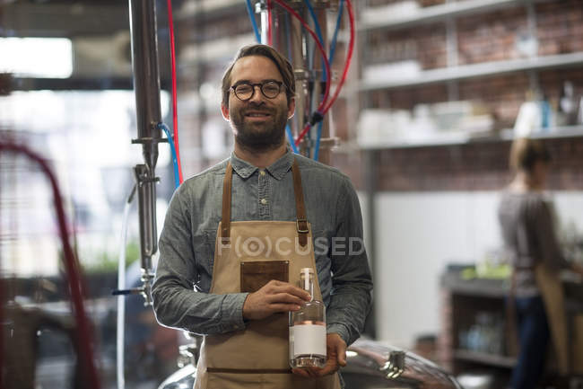 Sorrindo homem segurando garrafa na destilaria — Fotografia de Stock