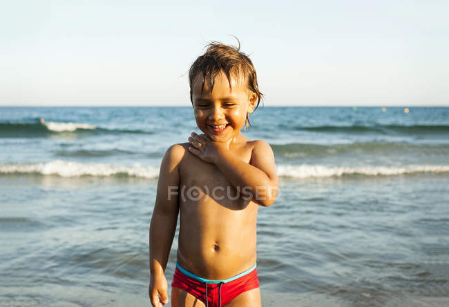 Niño feliz de pie frente al mar - foto de stock