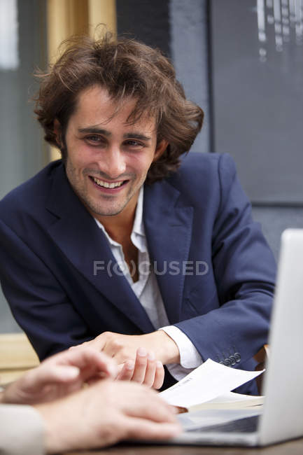 Jovem empresário sorrindo conversando no café da calçada — Fotografia de Stock