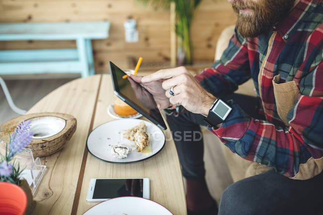 Uomo seduto nel caffè, utilizzando tablet digitale — Foto stock