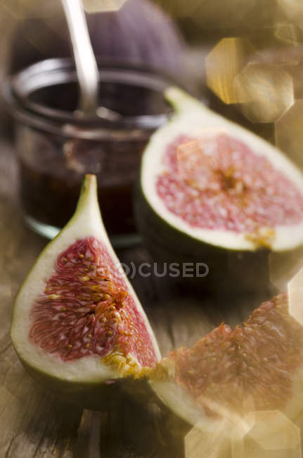Sliced fig and glass of fig jam on wooden table — Stock Photo