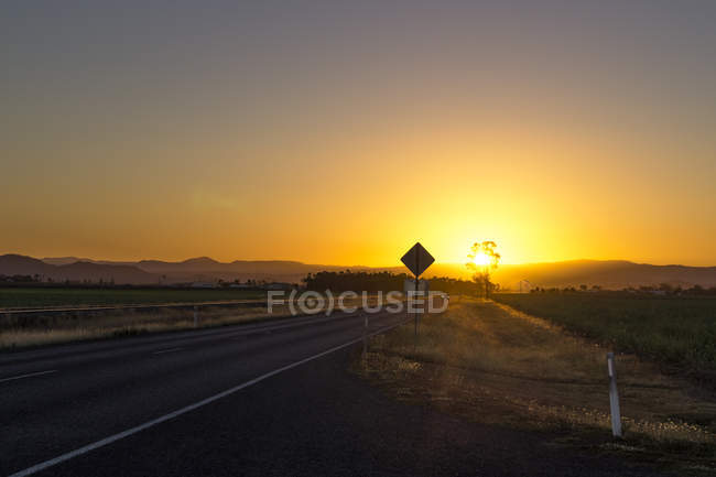 Australien, queensland, strasse mit bergkette bei sonnenaufgang — Stockfoto