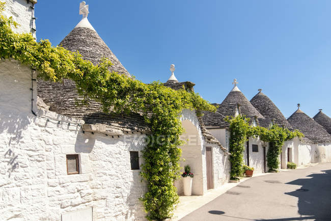 Italia, Apulia, Alberobello, Trulli, cabañas de piedra seca con techos cónicos - foto de stock