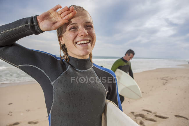 Smiling young woman with surfboard on the beach — Stock Photo