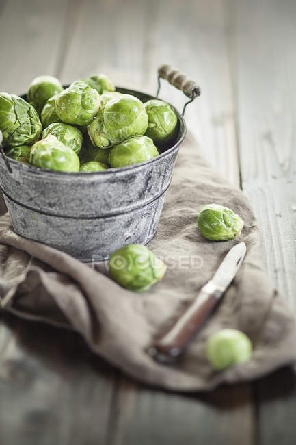 Peeled brussel sprouts in tin bucket, knife, studio shot — Stock Photo