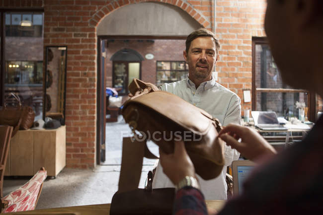 Uomo consegna borsa in pelle in negozio — Foto stock