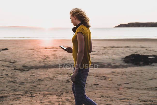 Дівчина-підліток використовує смартфон на пляжі — стокове фото