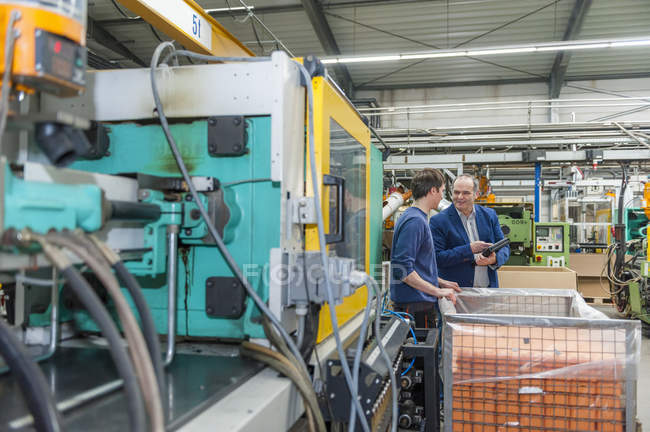 Manager und Arbeiter begutachten Kunststoffprodukte in Fabrik — Stockfoto