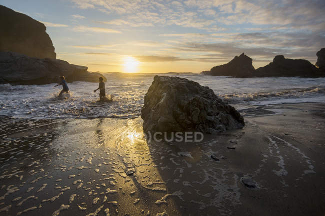 UK, England, Cornwall, Bedruthan Steps, two boys in the ocean at sunset — Stock Photo