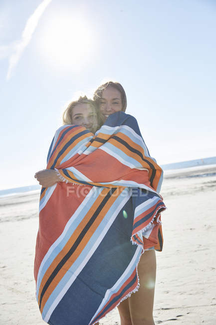 Dos hermosas amigas en toalla abrazándose en la playa - foto de stock